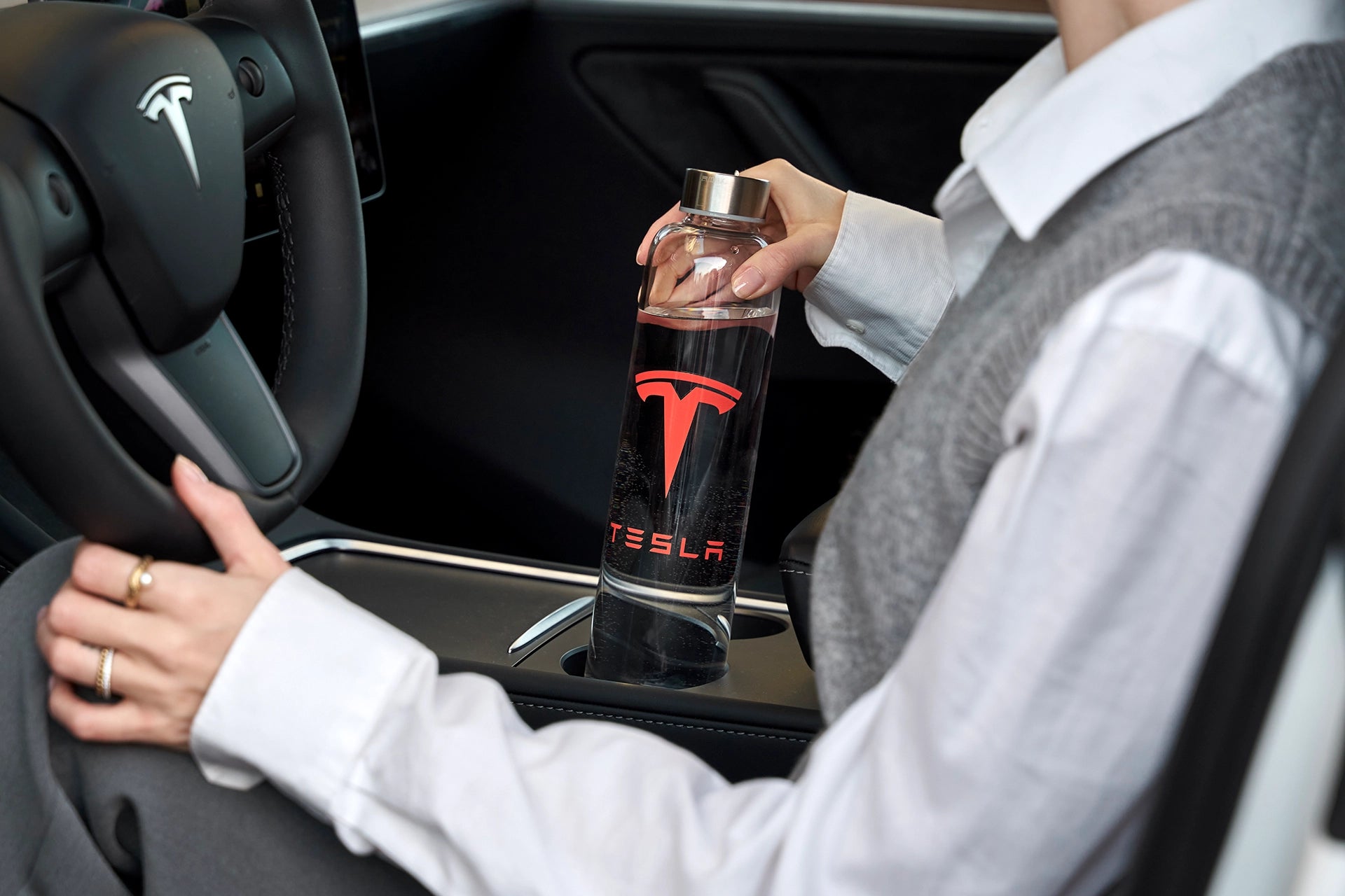 Trinkflasche aus glas mit einem tesla logo in einer Flaschenhalterung im Auto